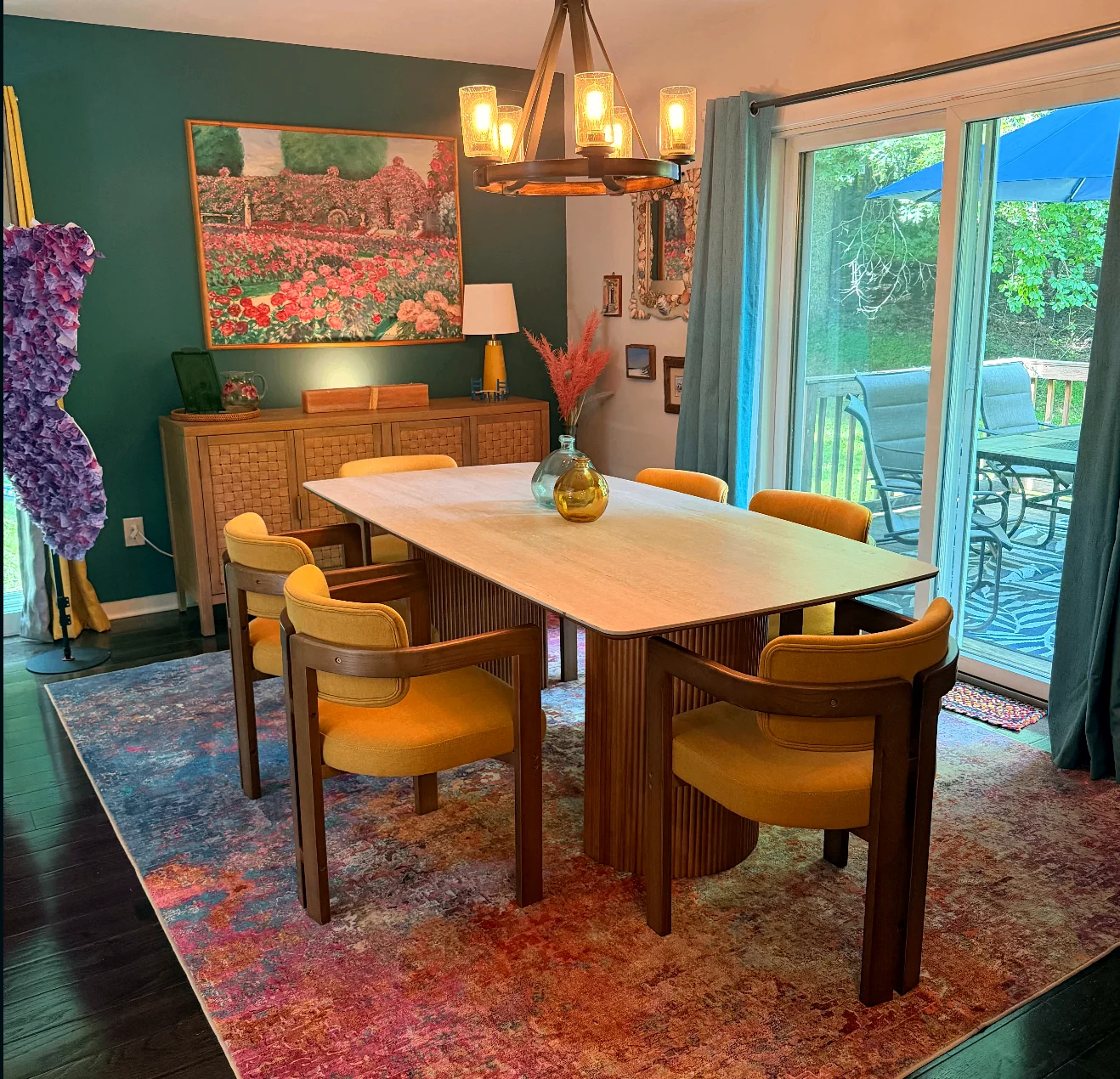 Dining room with a long wood table, teal walls, and glass doors