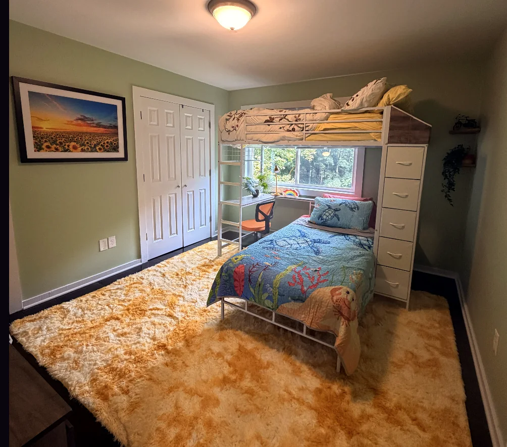 Green bedroom with two beds and windows facing the trees