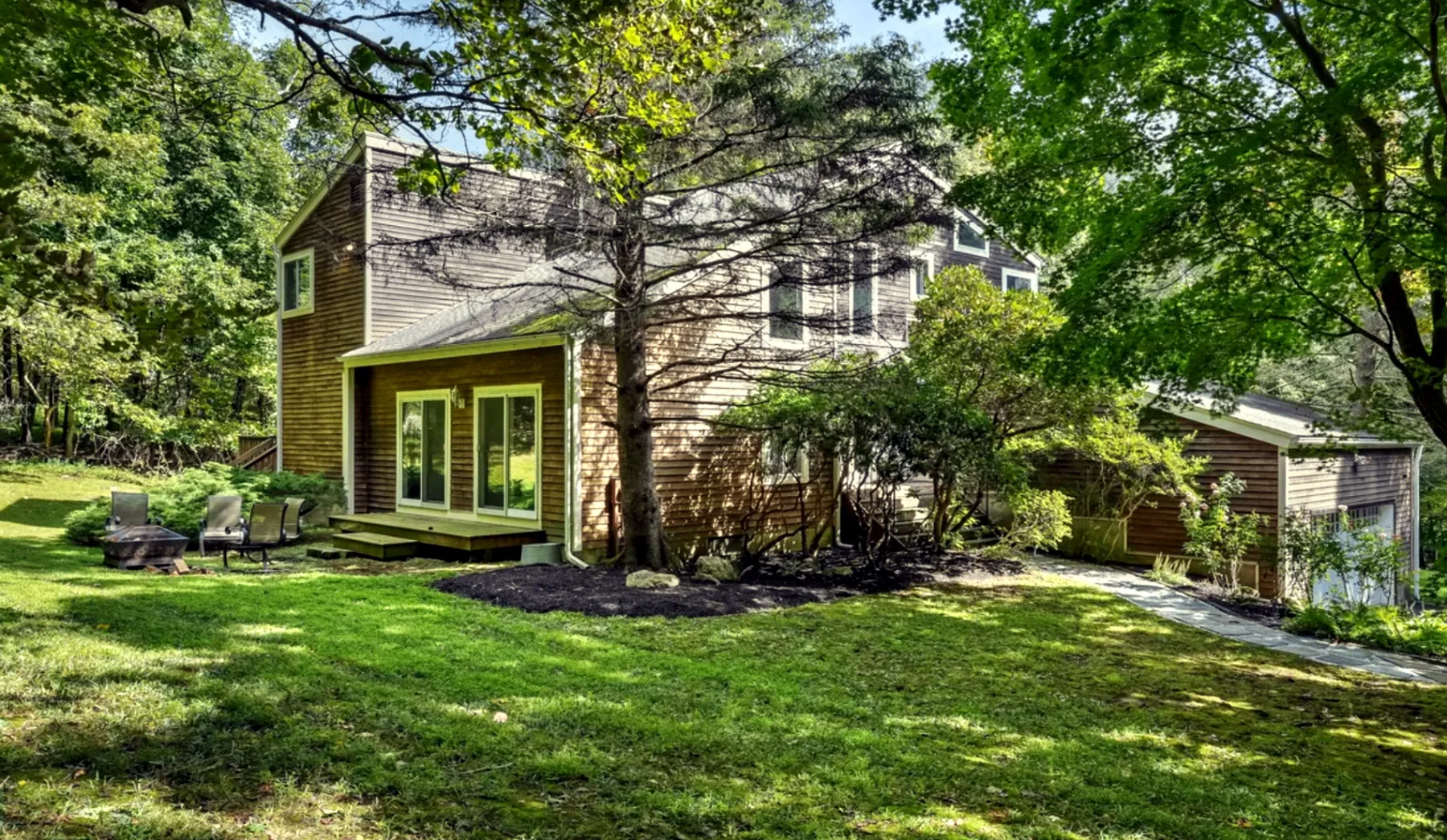Cedar-sided house nestled among mature green trees