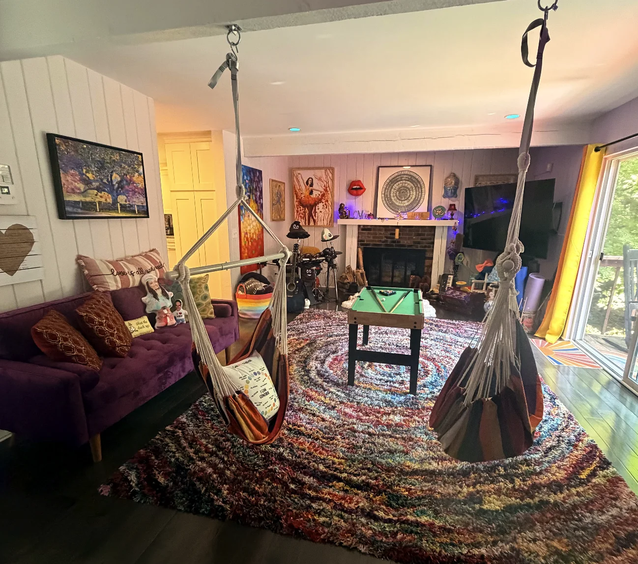 Colorful living room with a purple sofa, patterned rug, and hanging chair