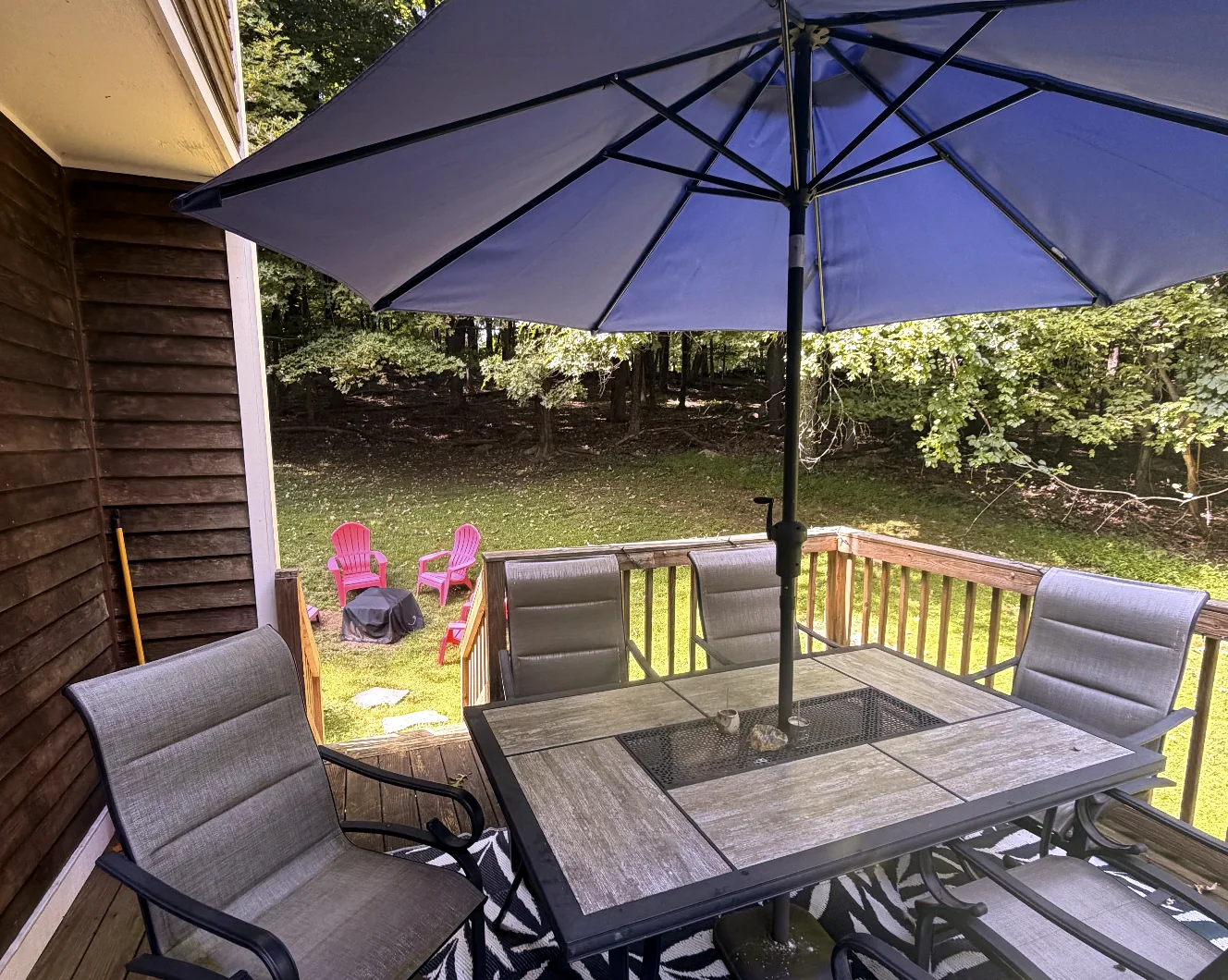 Outdoor dining table beneath a large umbrella on the deck